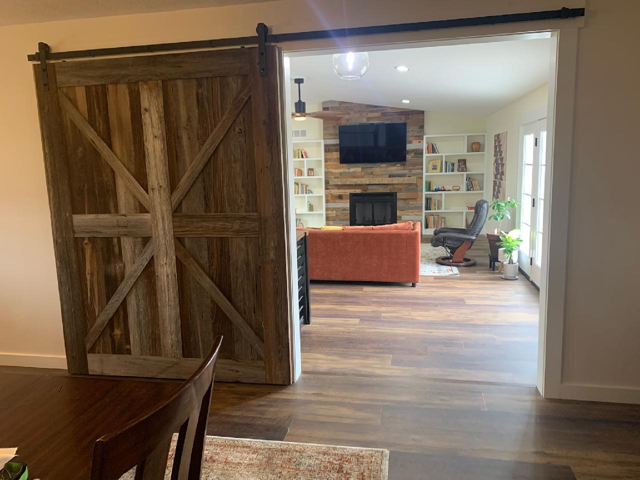 This project created a room divider adding  a custom built sliding barnwood door and walking into the den, they have chose a great selection of barnsiding for their fireplace wall and adding a one of a kind fireplace mantle to this space!