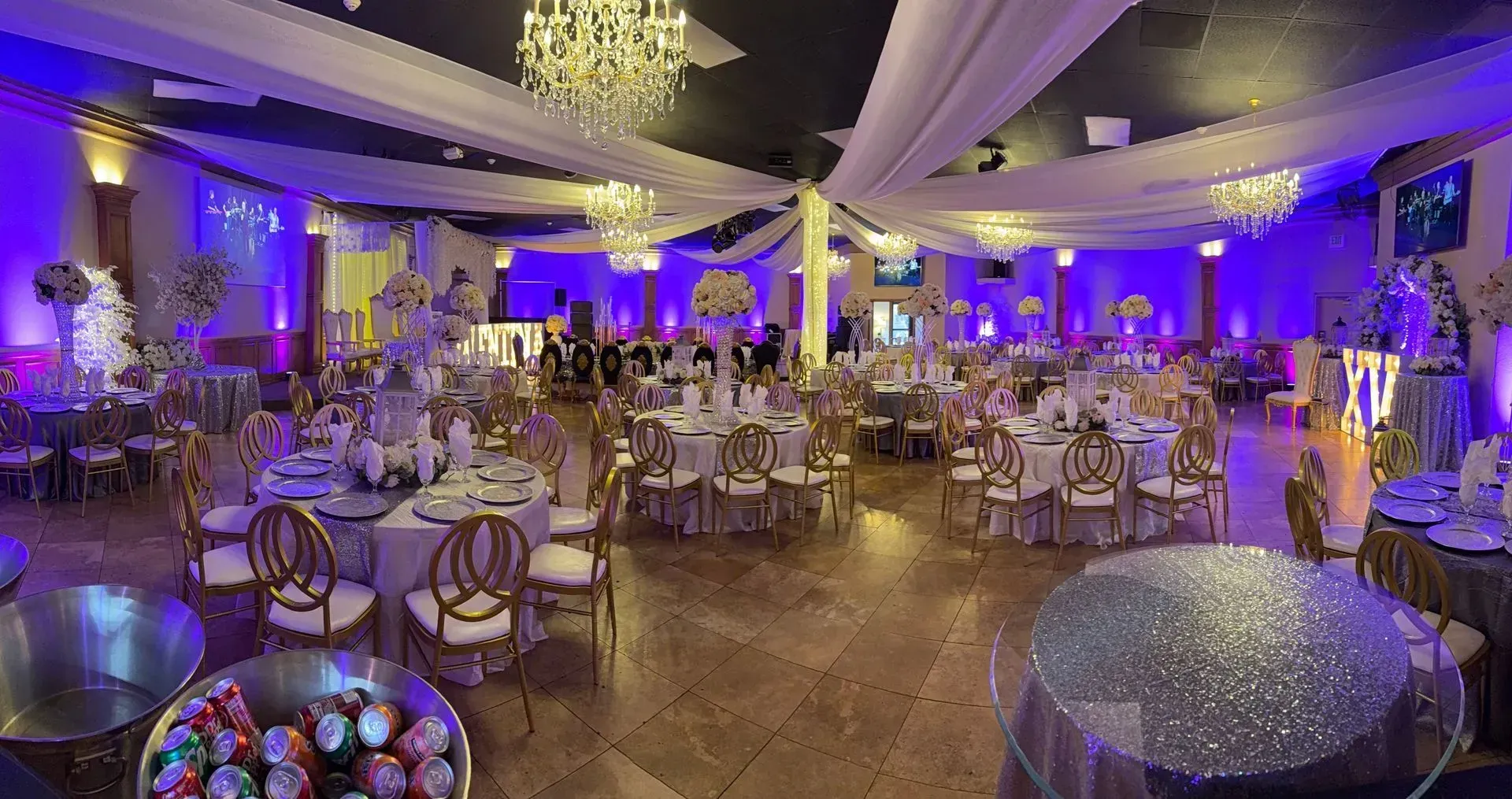 Elegant reception venue illuminated with purple uplighting, sparkling chandeliers, luxurious table s 