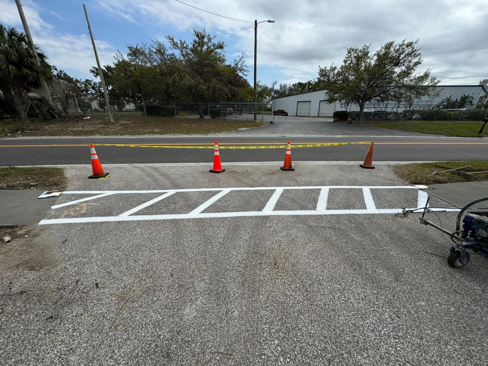 Newly painted pedestrian crosswalk markings installed across a commercial driveway, improving visibility and pedestrian safety.