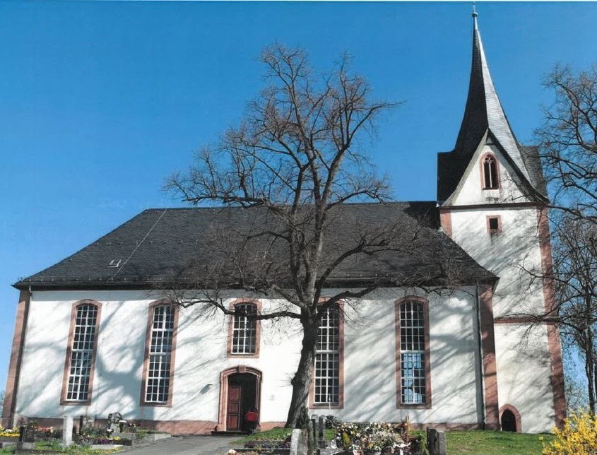Auf einer über dem Dorf gelegenen Basaltkuppe steht weithin sichtbar die von einem ummauerten Kirchhof umgebene Kirche.
Der Turm gehört noch in die erste Hälfte des 13. Jahrhunderts, während die vier massiven Dreiecksgiebel mit spätgotischen Maßwerkfenste