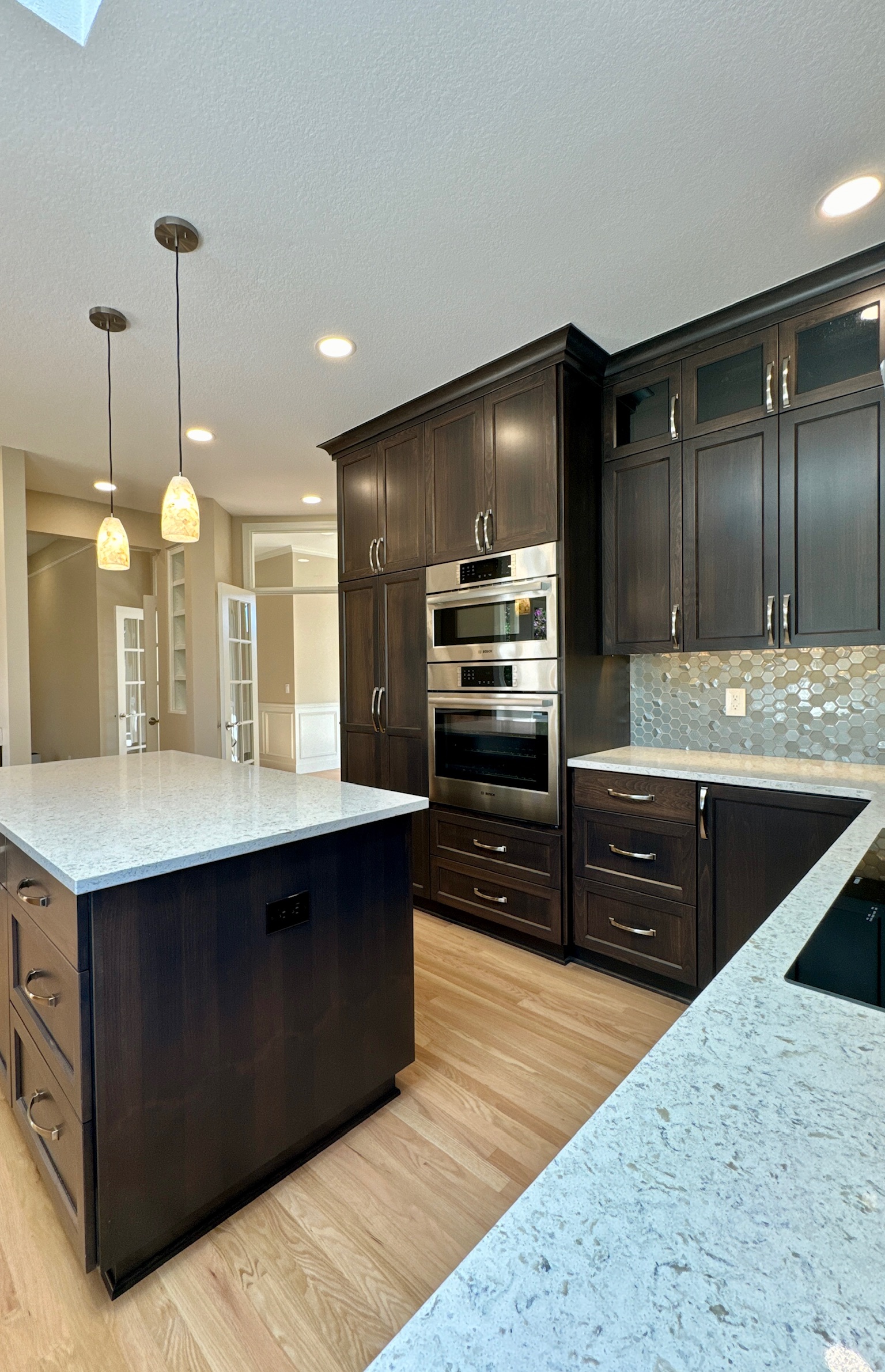 High-end kitchen remodeling project completed by Jason Smith Construction featuring dark custom cabinetry, quartz countertops, hardwood flooring, modern pendant lighting, built-in stainless appliances, and a large center island in Clackamas County, Oregon. Luxury kitchen renovation craftsmanship for homeowners in Canby, Wilsonville, Oregon City, West Linn, Molalla, and surrounding Northwest Oregon communities.