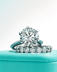 Photograph featuring an elegant engagement diamond ring stacked with a wedding band on top of a Tiffany & Co. box