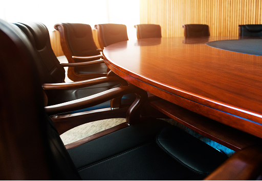 Boardroom table surrounded by chairs.