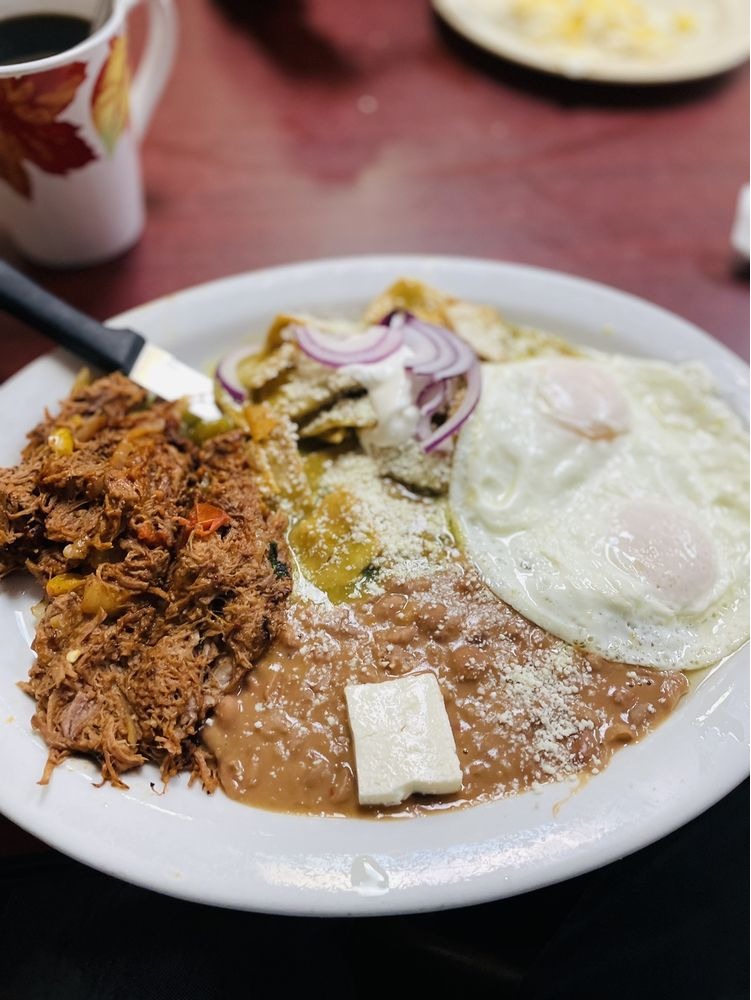 Mexican breakfast plate from Yolys Mexican Kitchen featuring savory machaca, two fried eggs, refried beans with cheese, and green chilaquiles topped with red onion and crumbled cheese.
Desayuno mexicano de Yolys Mexican Kitchen con machaca, dos huevos estrellados, frijoles refritos con queso y chilaquiles verdes acompañados de cebolla morada y queso desmoronado.