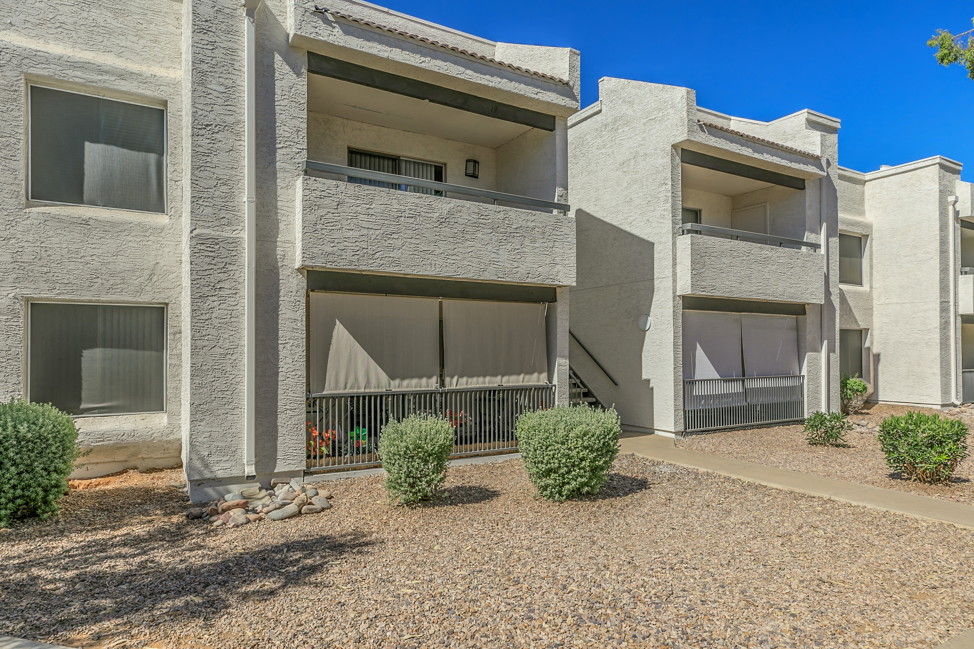 an exterior view of two apartment buildings with a gravel courtyard