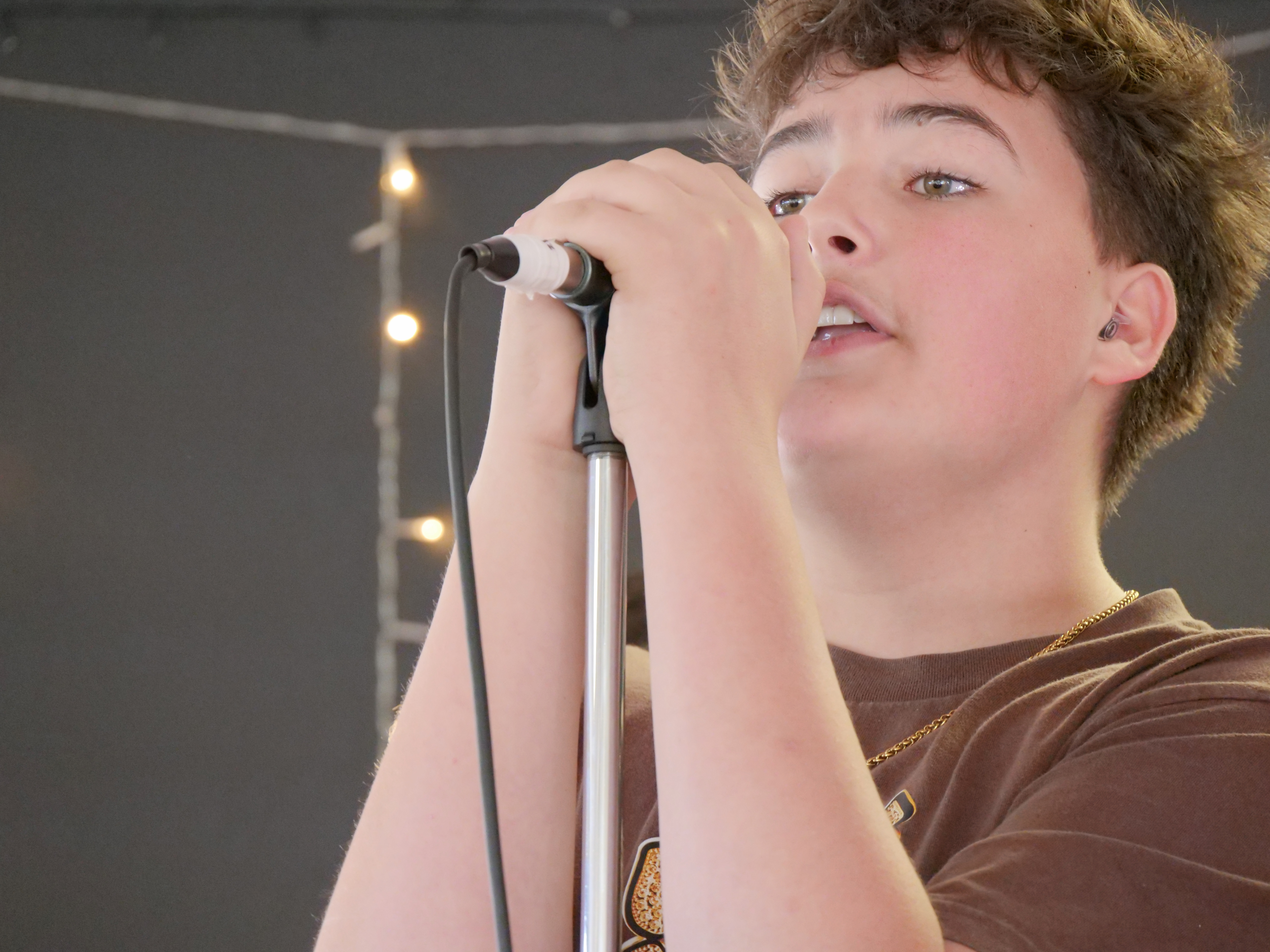 Young vocalist singing on stage as part of a live music and vocal performance program.
