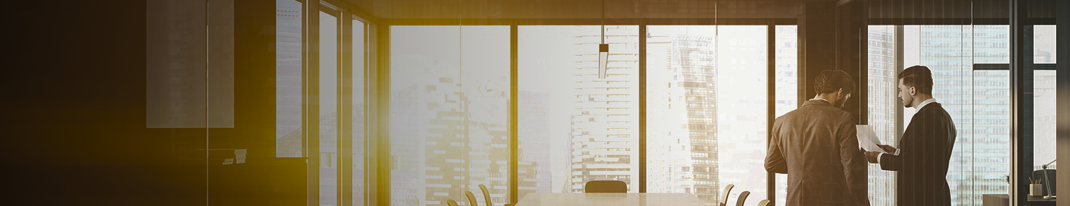 Two professionals having a discussion in an office boardroom.