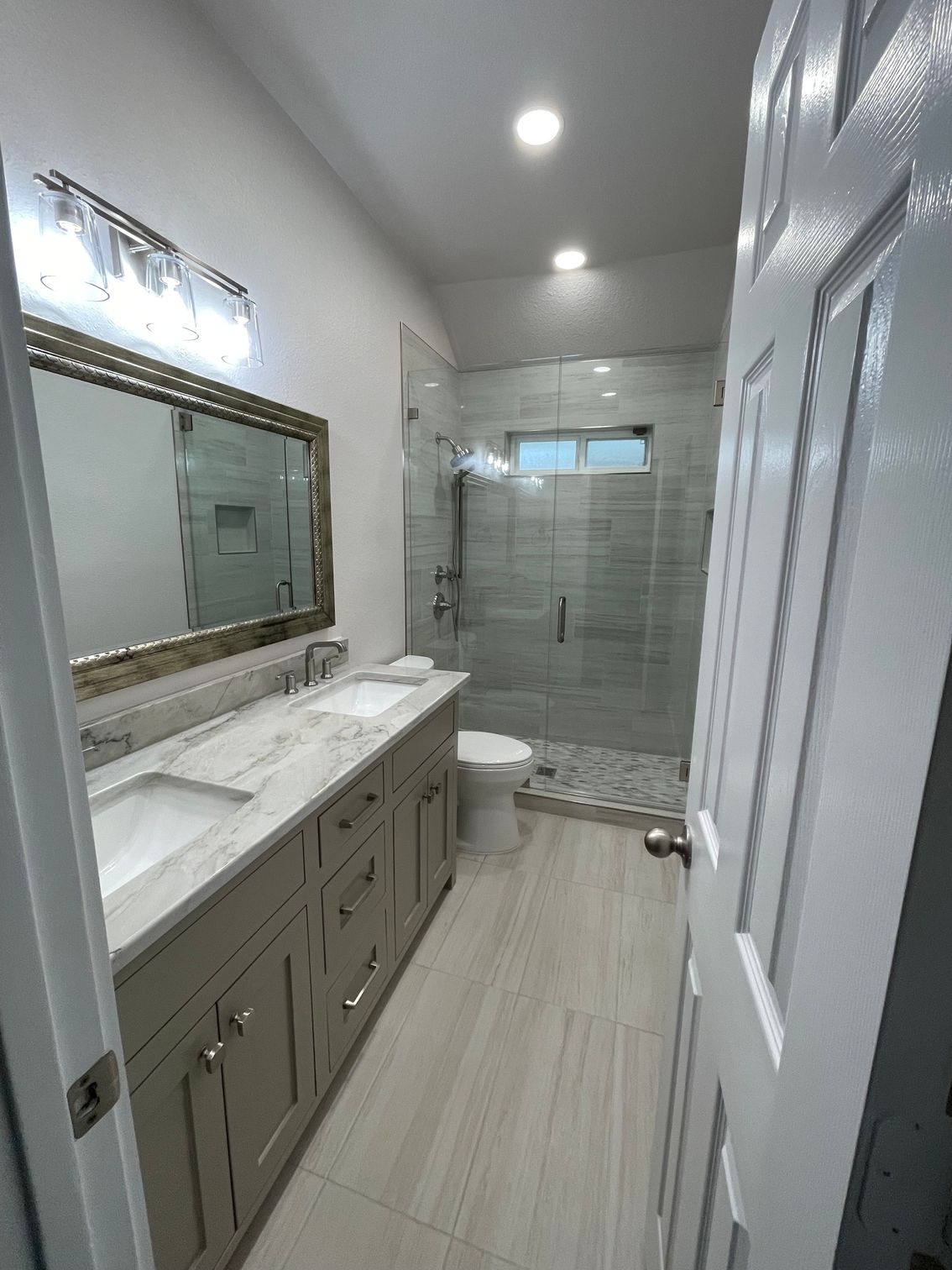Modern bathroom renovation featuring a long vanity with marble countertop, double sinks, contemporar 