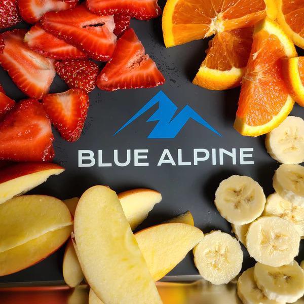 This vibrant image showcases a variety of freshly sliced fruits beautifully arranged around a central logo. The “BLUE ALPINE” text and emblem are sharply contrasted against the colorful backdrop, making it an eye-catching centerpiece. The fruits, including strawberries, bananas, apples, and oranges, are vivid and inviting, highlighting their natural appeal.