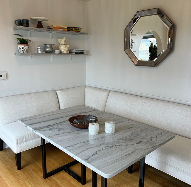 A cozy sitting area features a curved cream sectional, marble-patterned coffee table, decorative she 