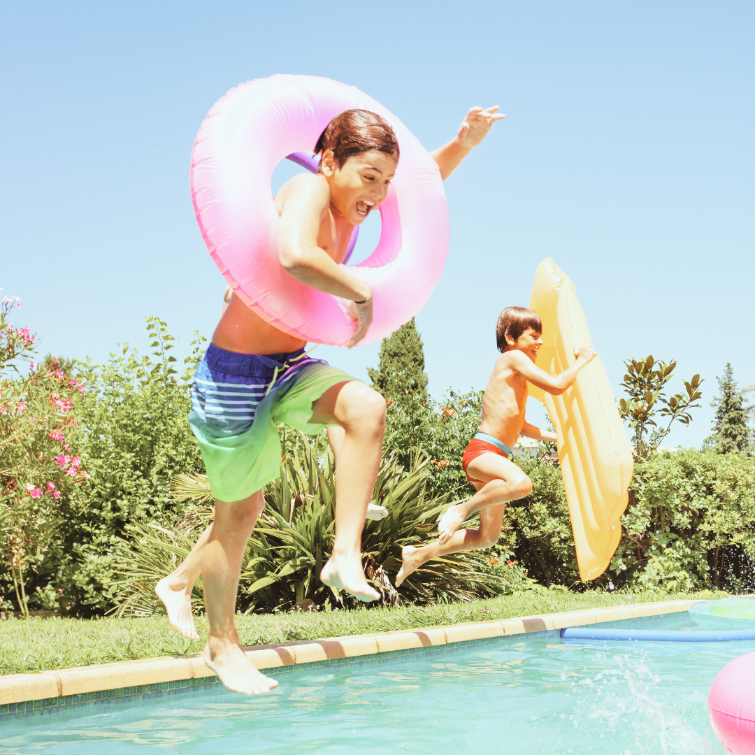 Kids having a blast jumping into a sparkling clean pool on a sunny day