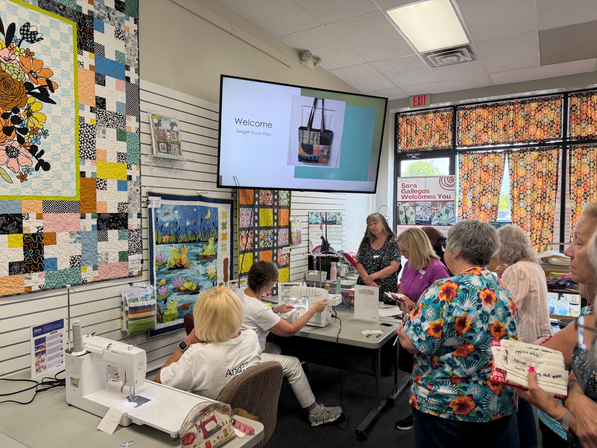Participants attend a Decorative Stitch Serger Sock Hop class, learning creative serger techniques through a live demonstration. This hands-on workshop inspires confidence, creativity, and new sewing skills.