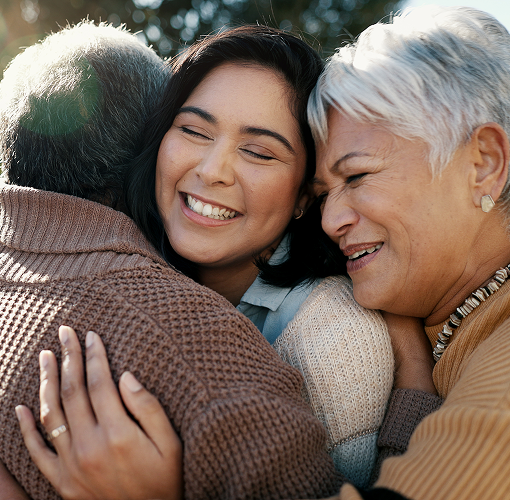 A daughter hugging her elderly parents.