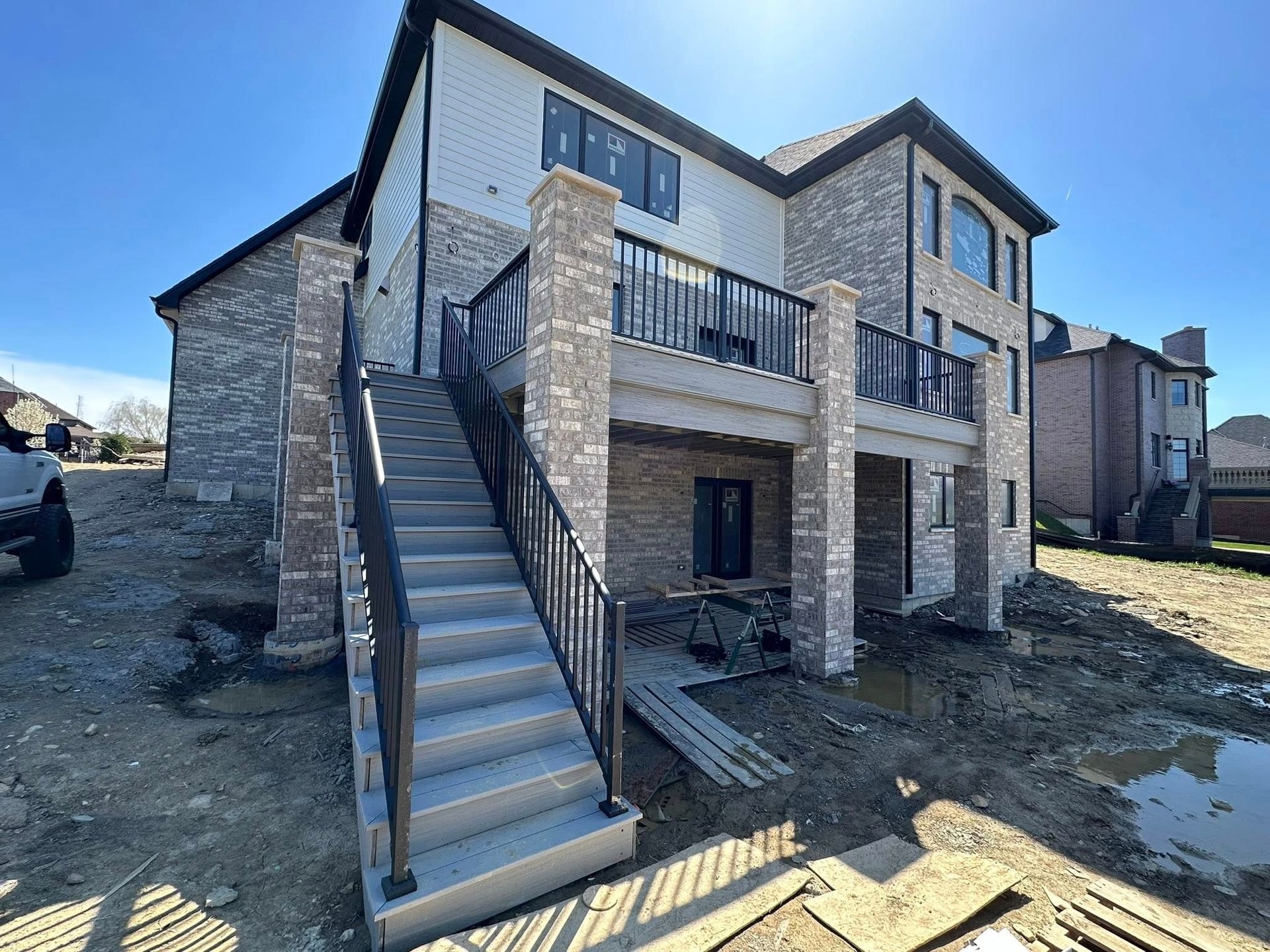 A newly constructed elevated deck features composite decking, sturdy support columns, modern railings, spacious outdoor living areas, professional craftsmanship, and durable construction designed for long-term residential enjoyment.