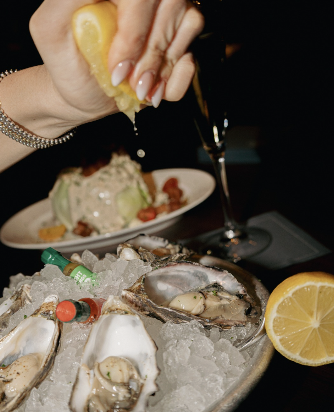 Lemon being squeezed on fresh oysters.