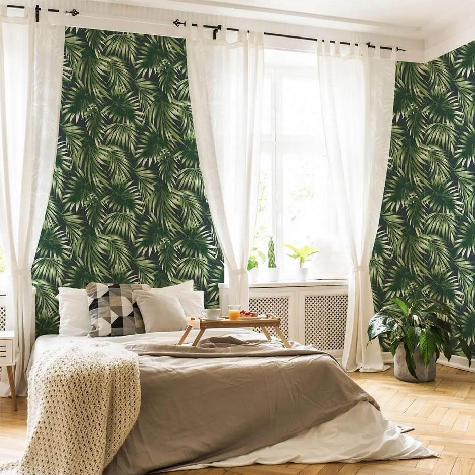 A bedroom with wallpaper in green leaves