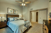 Carpeted bedroom with ceiling fan, vaulted ceiling, walk-in closet and hallway to bathroom.