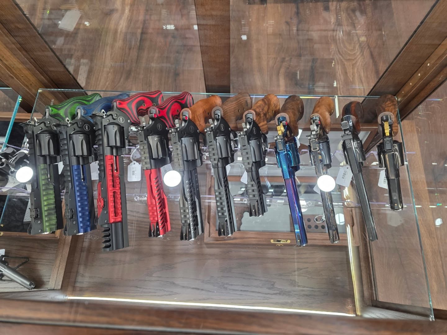 Modern custom revolvers in striking finishes — from titanium blue to bold reds and greens — part of Shoot It LLC's diverse firearms inventory in Phoenix.