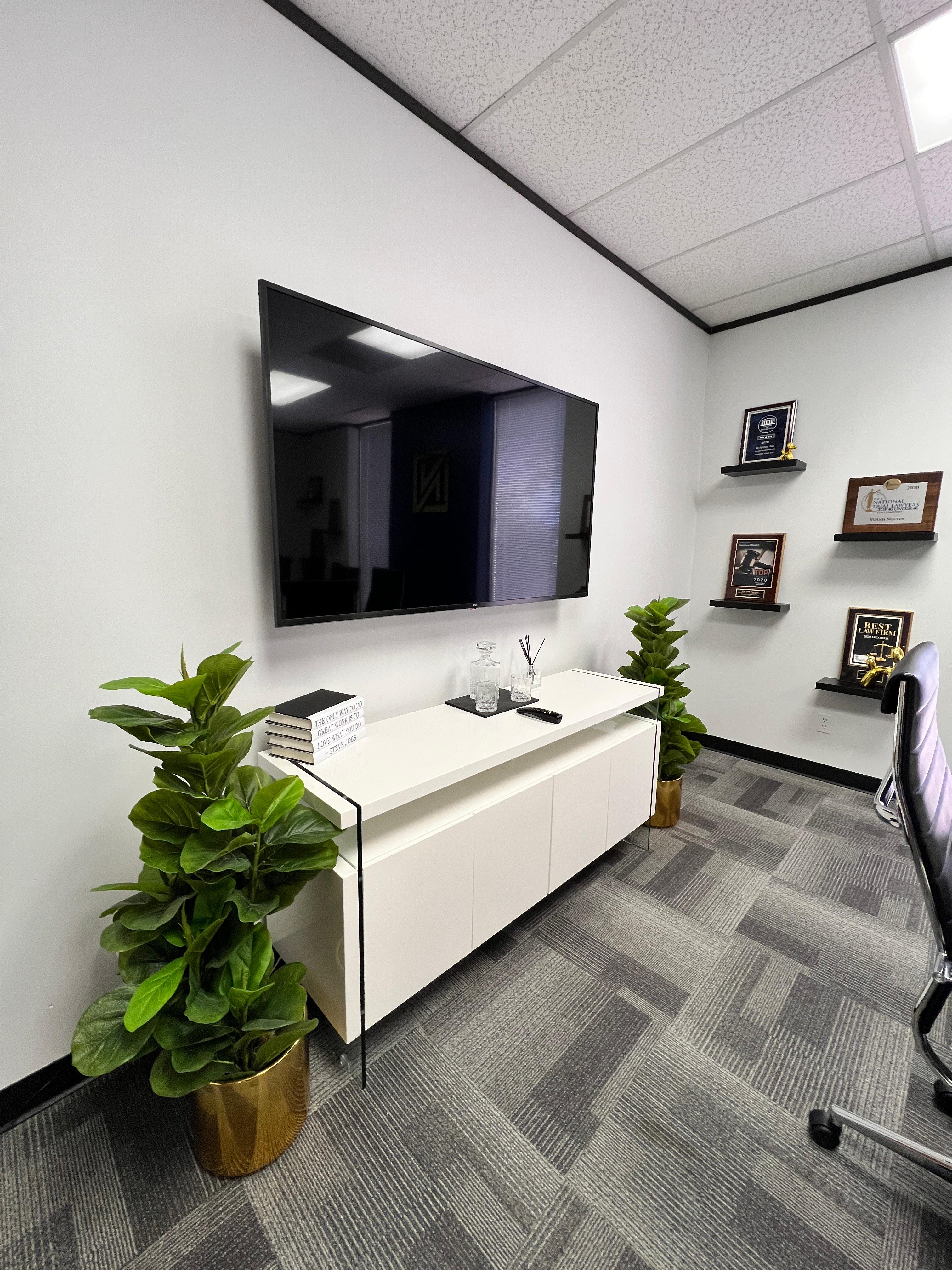 Commercial office with wall-mounted TV, white cabinet, and floating display shelves.