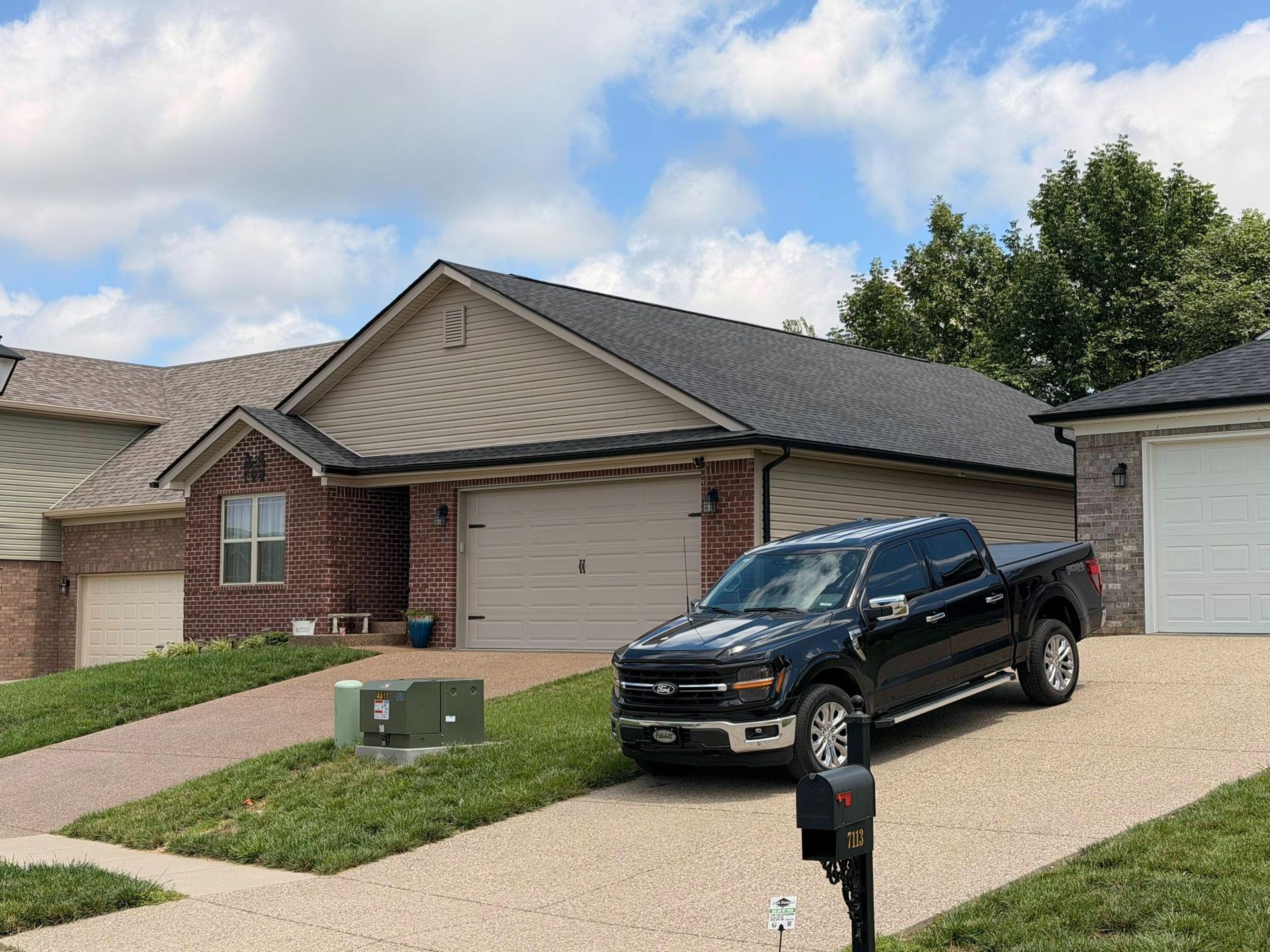 Front view of a modern suburban home with a newly installed charcoal asphalt shingle roof providing  