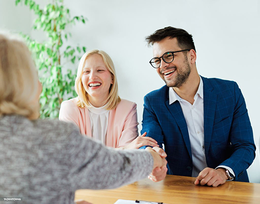 A couple smiling while meeting with an advisor.