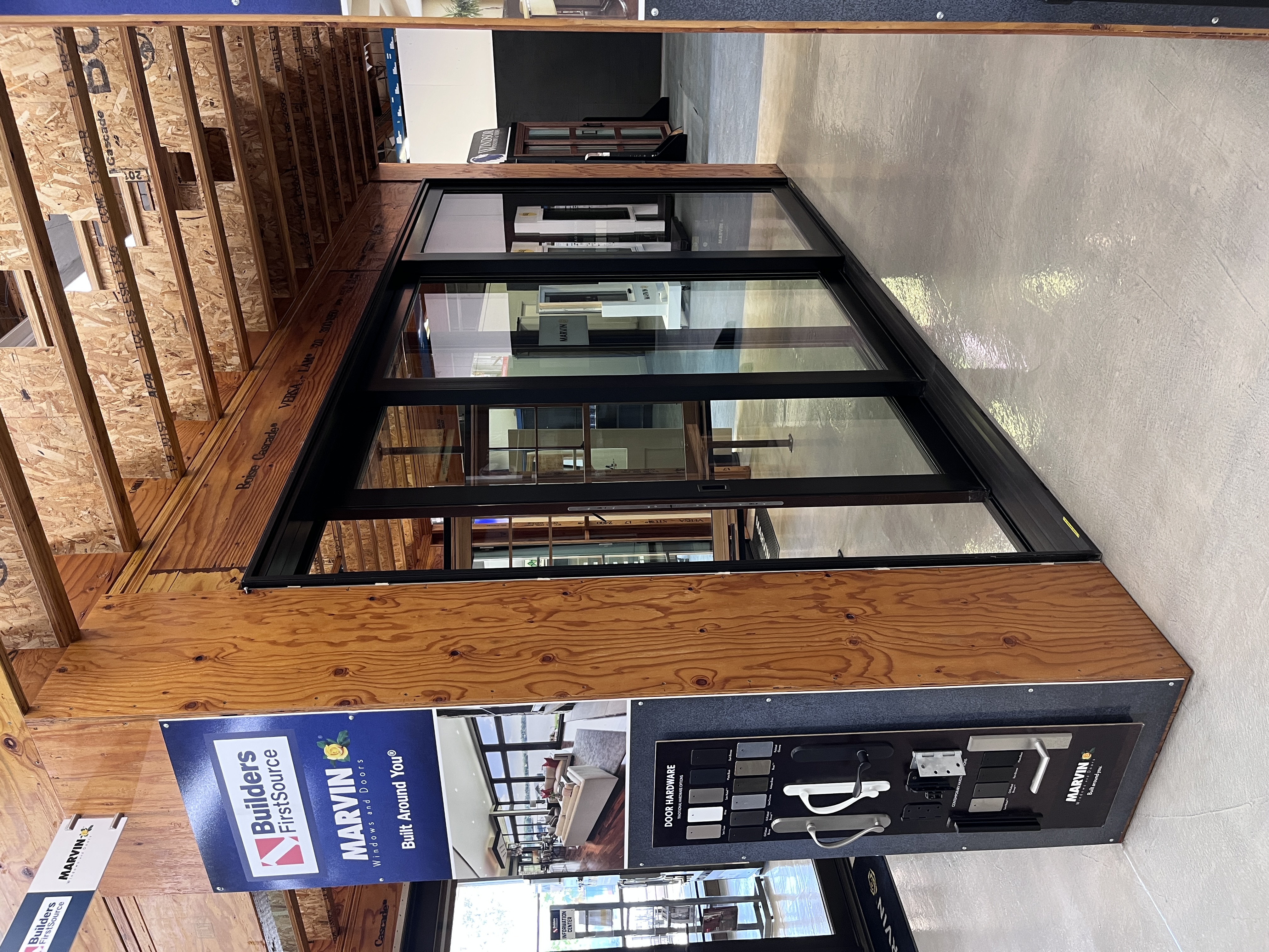 Marvin window and door showroom display at Builders FirstSource Thousand Oaks, CA, featuring a black-framed sliding door and a door hardware finish sample board.