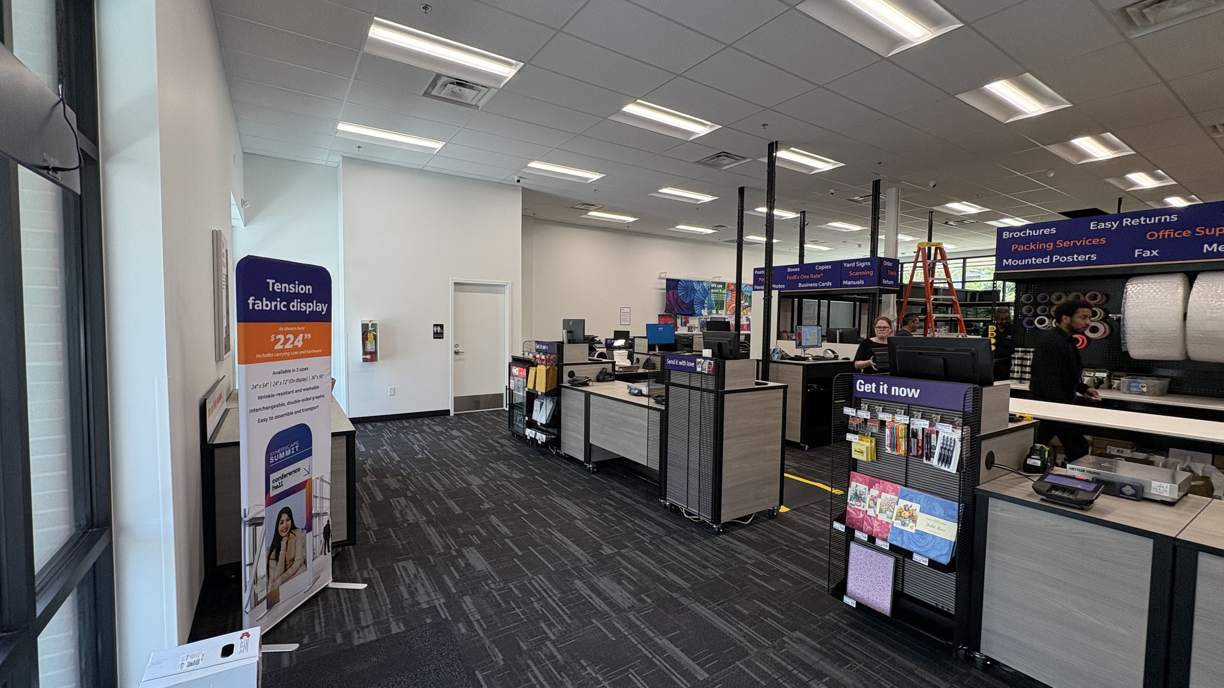 View down the main aisle of the FedEx Office in Atlanta, GA, showing the flow from the entrance to the service counters.