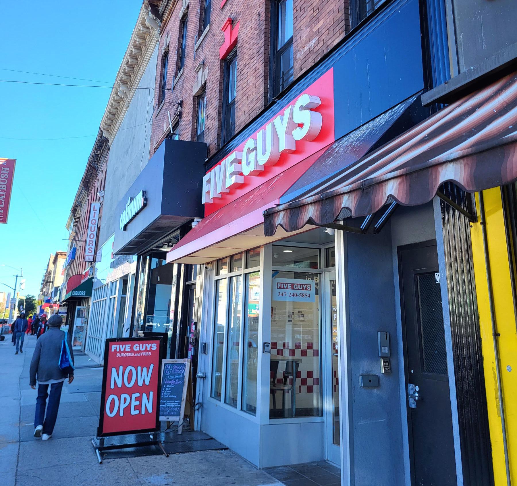 Exterior photograph of the entrance to the Five Guys restaurant at 2133 Nostrand Avenue in Brooklyn, New York.