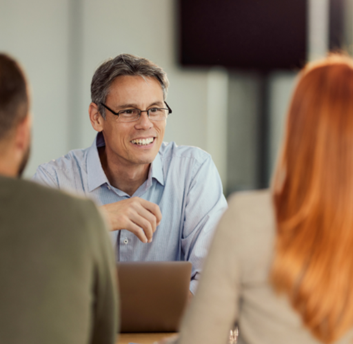A wealth advisor speaking with two clients during a meeting.
