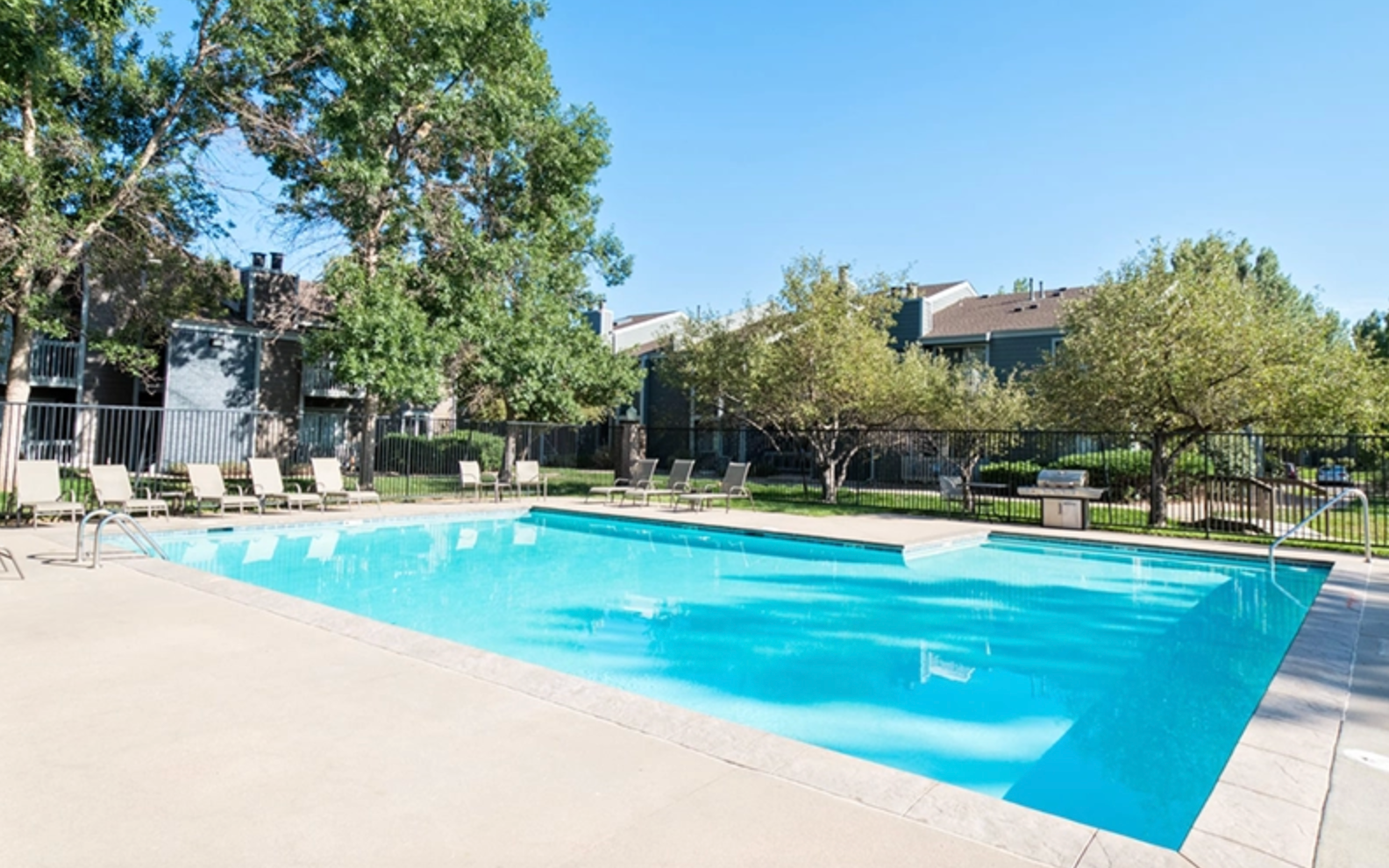 Swimming pool with large sundeck and lounge chairs.