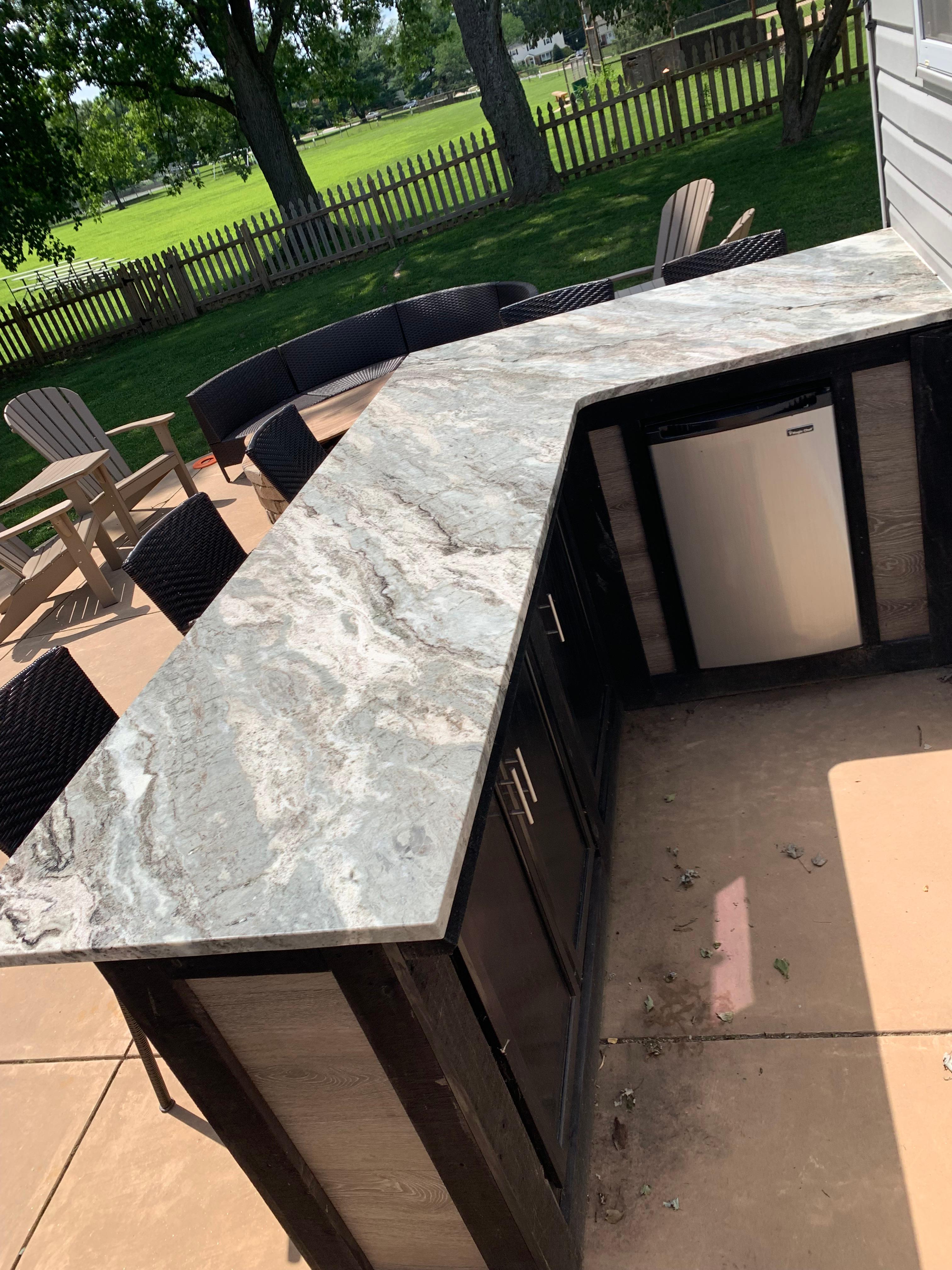 Updated stone outdoor kitchen with built in mini fridge.