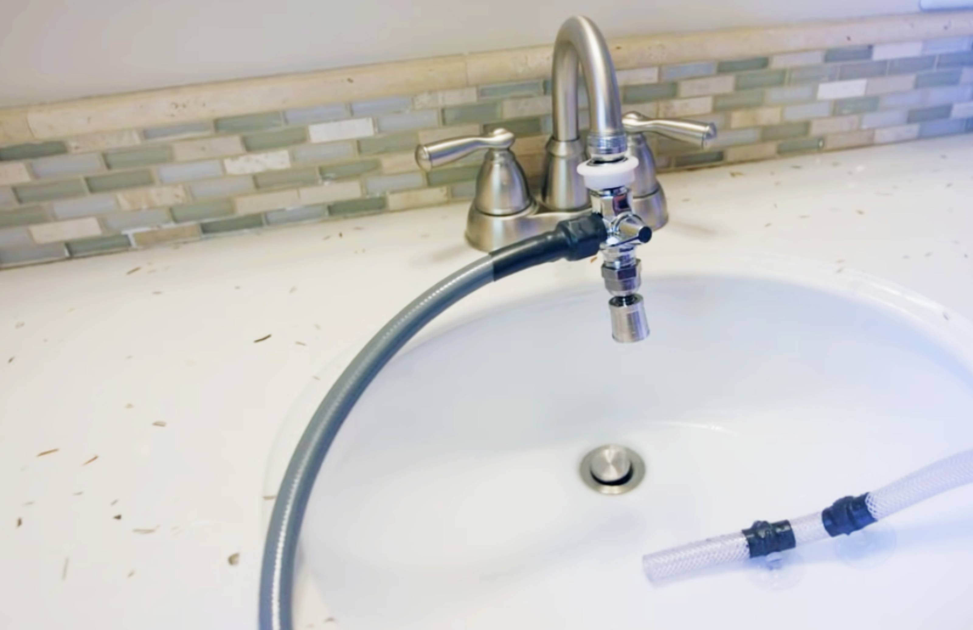 Close-up view of the Shower Bay drain and water connection system, showing how the portable shower is designed for easy setup and practical indoor use.