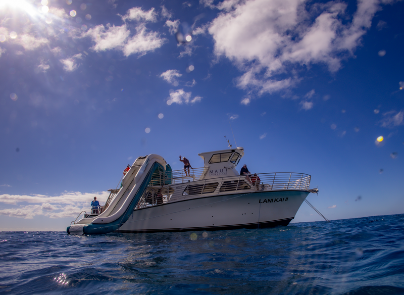 Guests enjoying the slide on a Maui Snorkeling Tour in clear Hawaiian waters