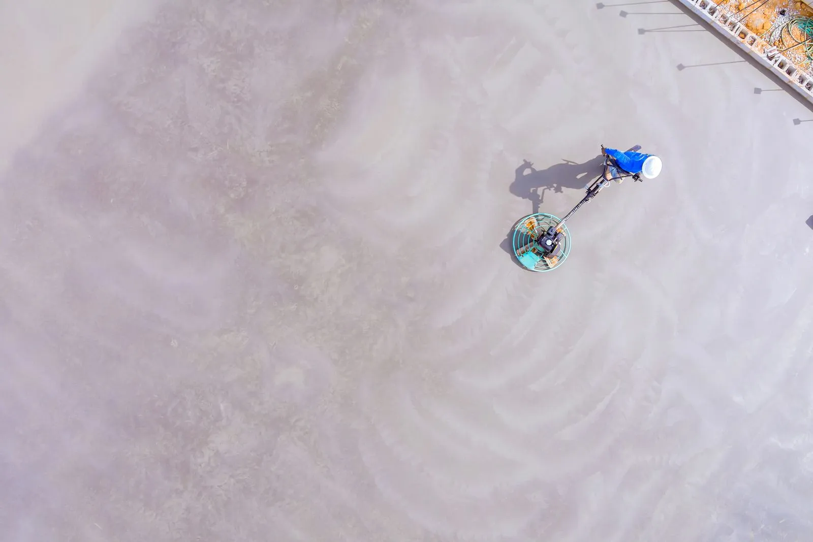 Aerial view of a commercial floor scrubber cleaning a large concrete surface, delivering uniform res 