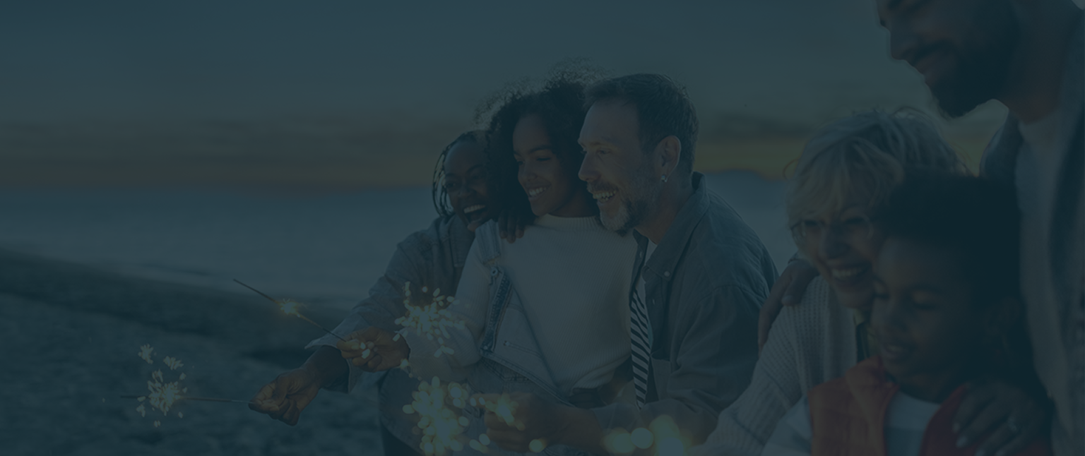 A multigenerational family playing with sparklers on the beach.