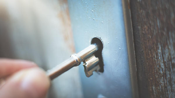A traditional style door key being placed into a lock