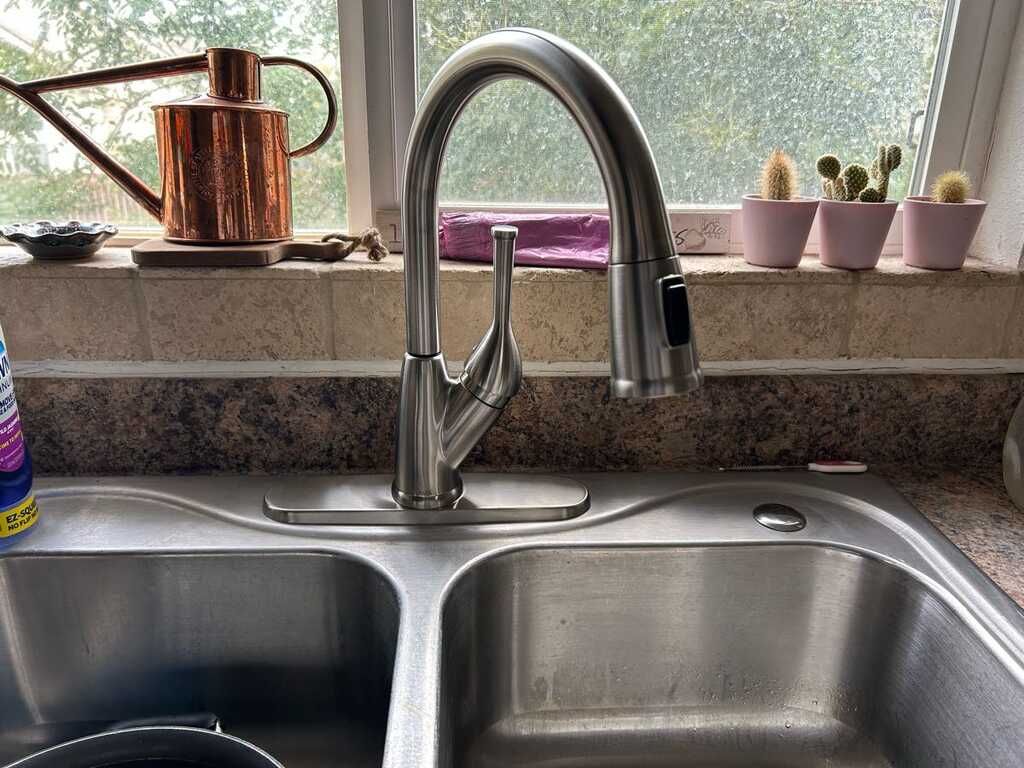 Stainless steel double kitchen sink features a modern pull down faucet beneath a bright window, with 