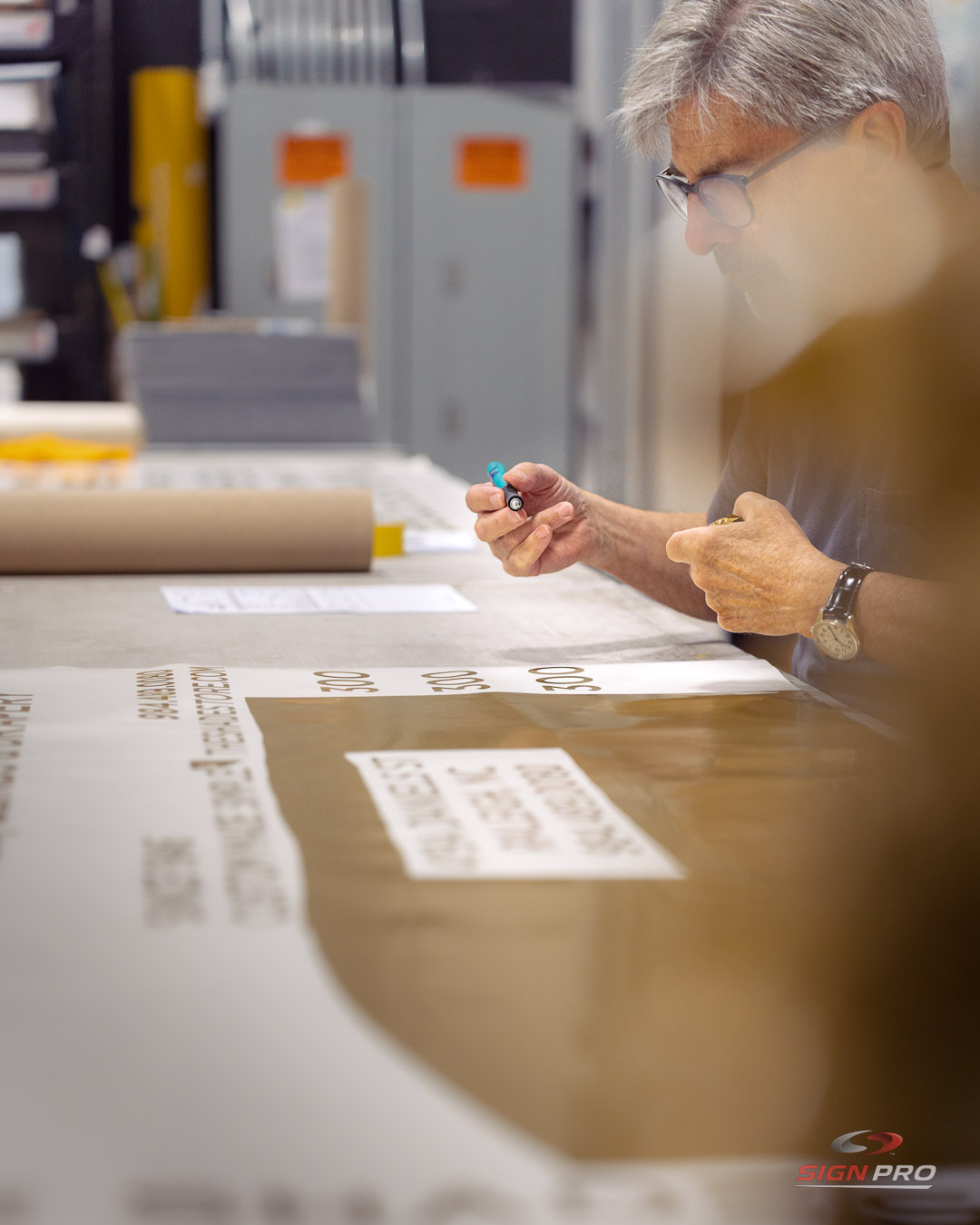 A Sign Pro technician meticulously weeds vinyl graphics for a signage project, ensuring high-quality letter and number application during the final production stages.
