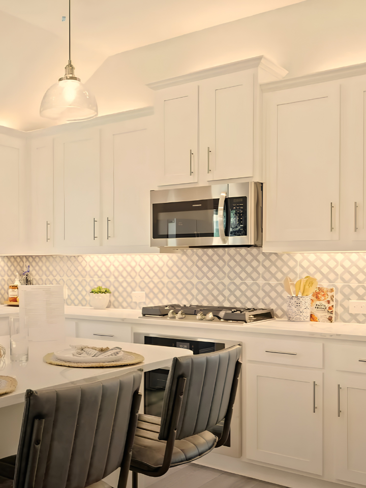 White shaker kitchen cabinets paired with stainless steel appliances, a hexagon tile backsplash, under-cabinet lighting, and a large island for everyday functionality.