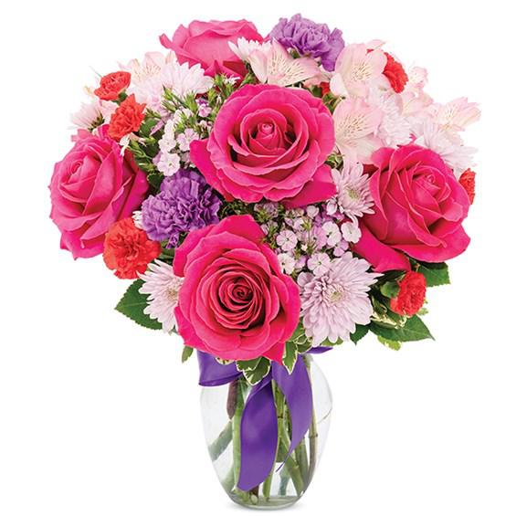 Love Is In The Air - Love will surely be in the air when she receives this bouquet with hot pink roses, red mini carnations, lavender poms, purple carnations, pink dianthus, and pink alstroemeria in an elegant clear vase.
