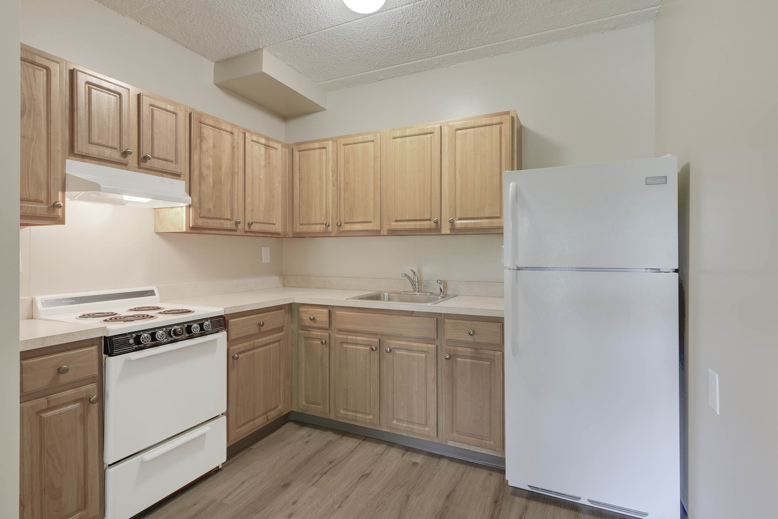 A kitchen with wooden cabinets and a white refrigerator.