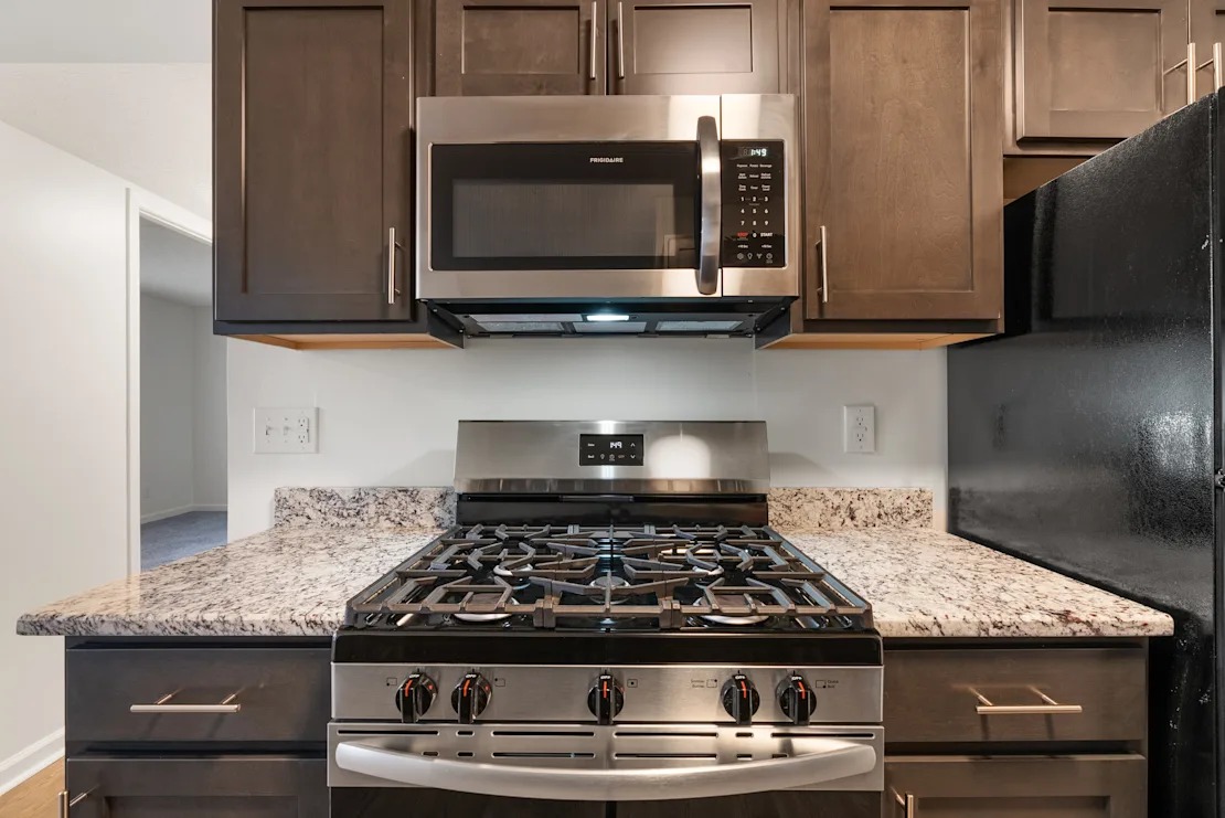 A black stove top oven with four burners and a stainless steel microwave