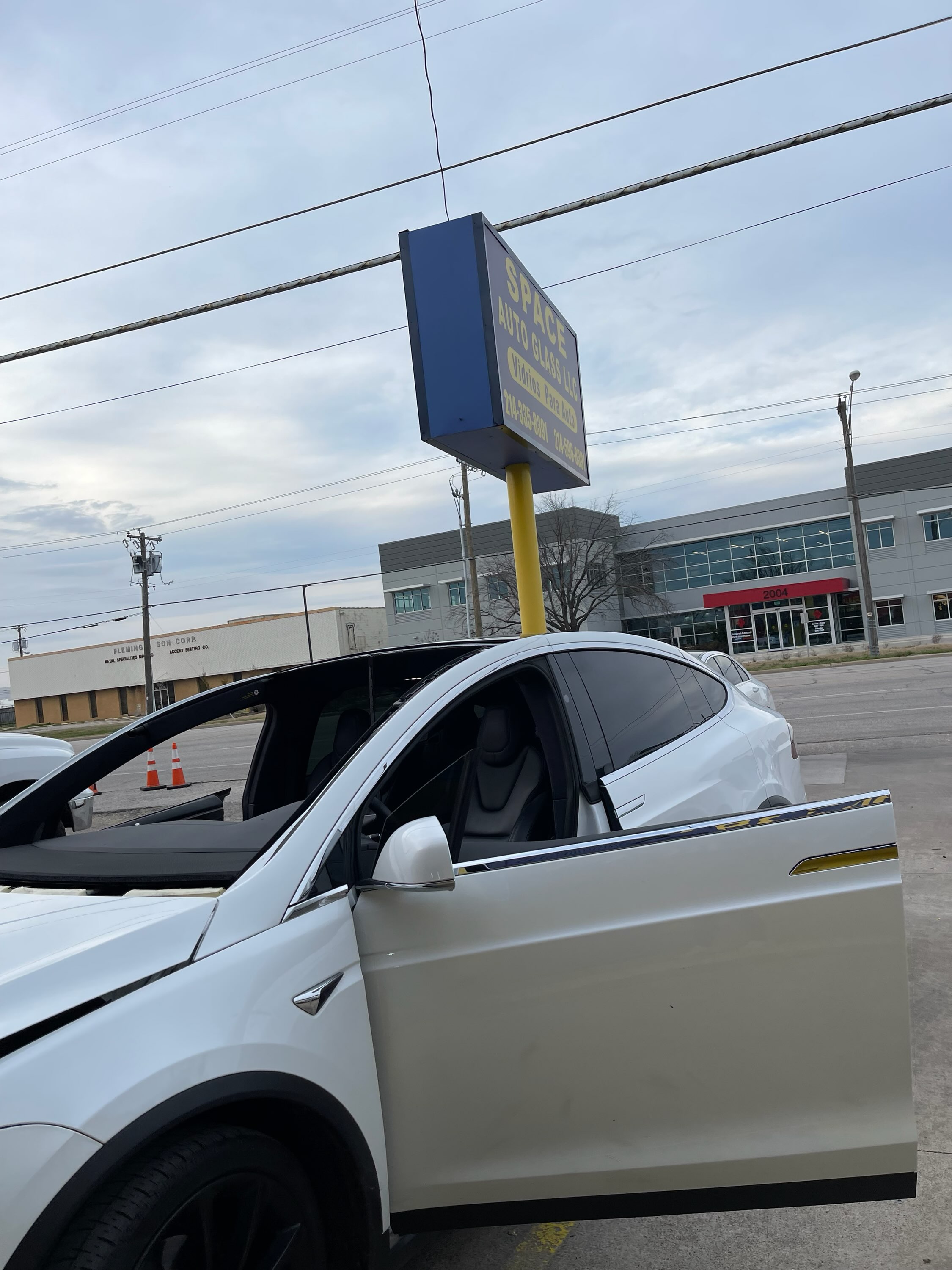 Close-up of a white Tesla with a long windshield crack and a marked impact point in the glass. The damage demonstrates why windshield replacement may be needed when cracks spread across a large portion of the windshield.