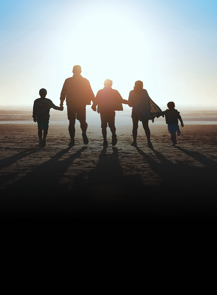 A family standing hand-in-hand during a sunset.
