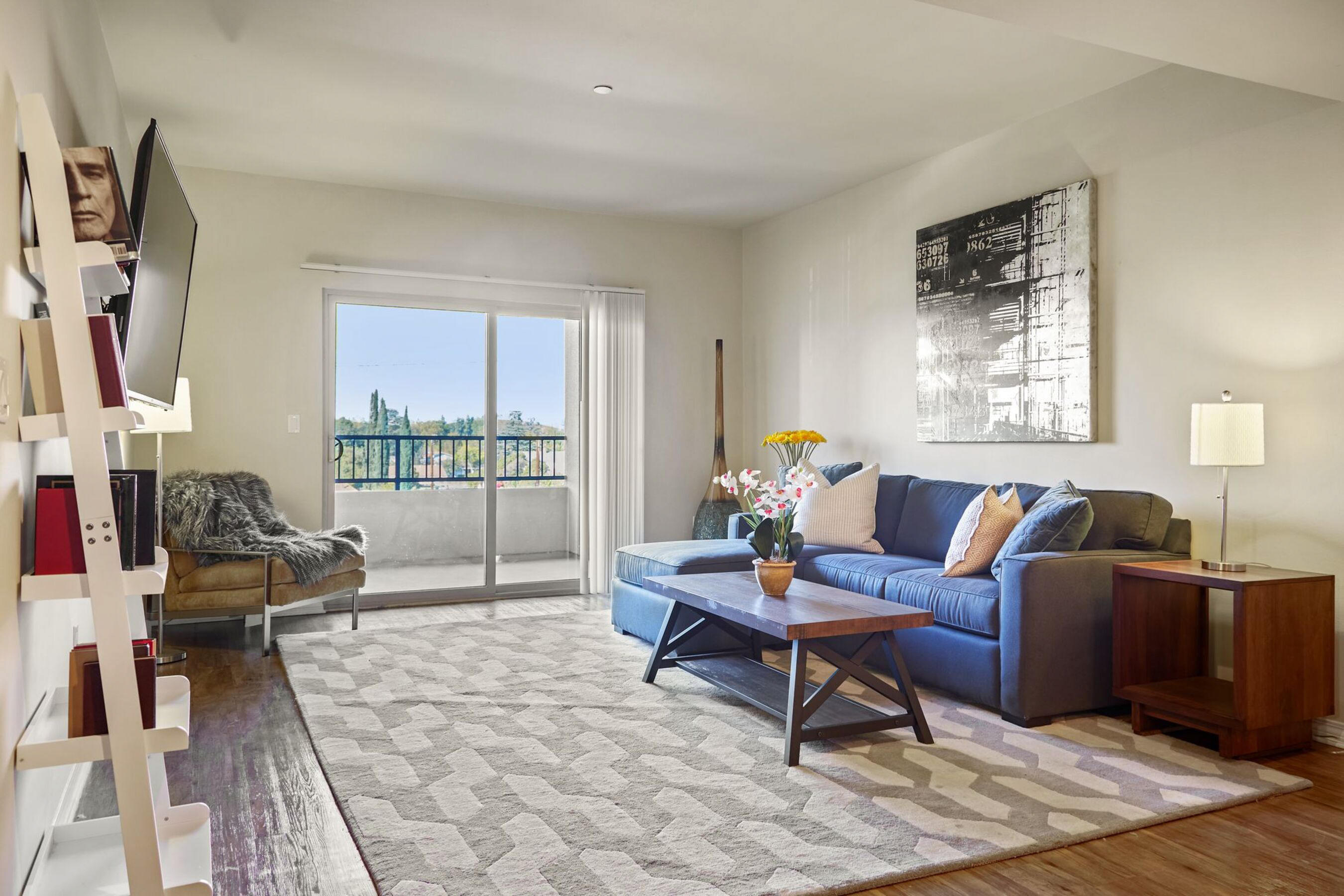 A living room with a blue couch and a grey rug. 