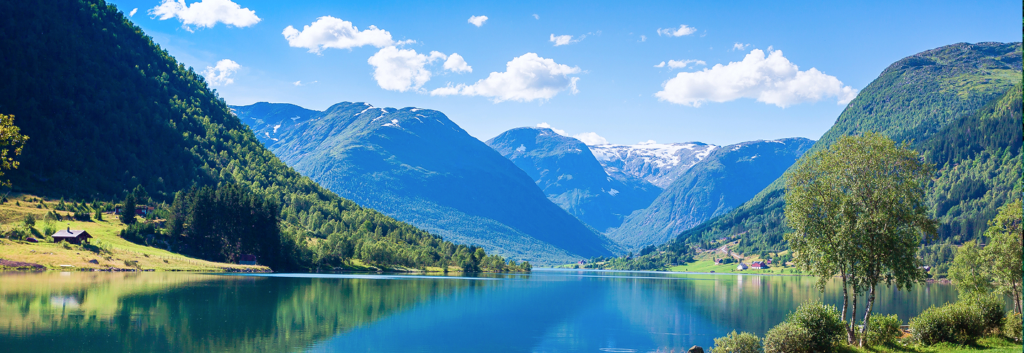 A calm, blue lake in a valley surrounded by mountains of lush forests.