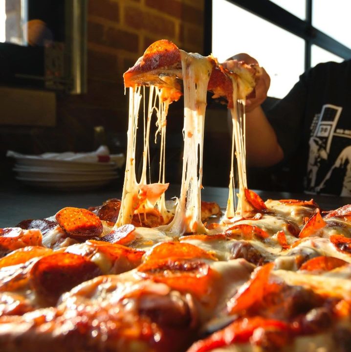 Person enjoying Paisans Pizza 