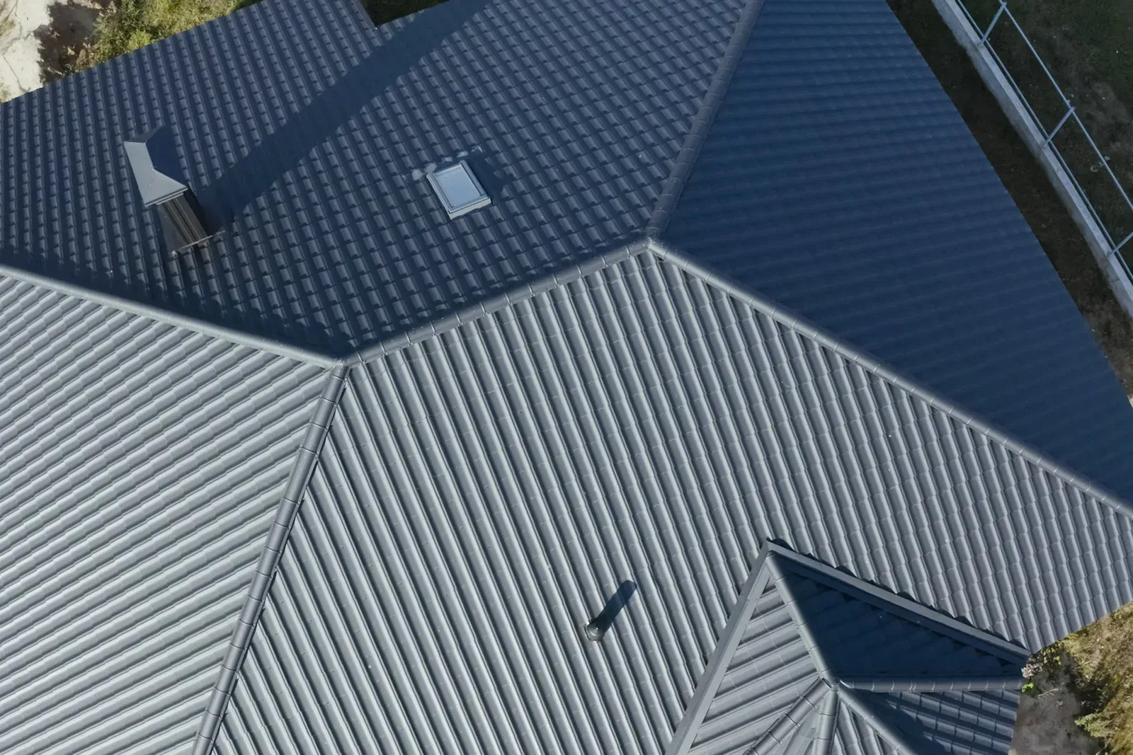 Aerial view of a professionally installed metal roofing system featuring multiple roof sections and precision craftsmanship. Durable materials provide long-term weather resistance, energy efficiency, and attractive appearance.