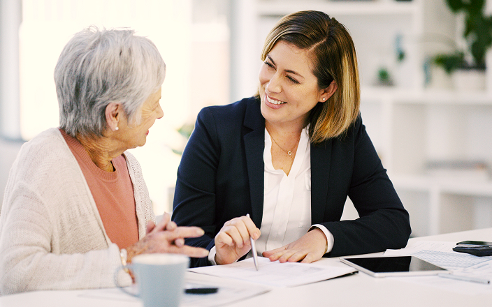 An advisor sitting down with an elderly woman client.