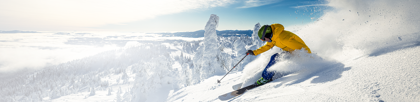 Action shot of someone downhill skiing with a picturesque alpine view.